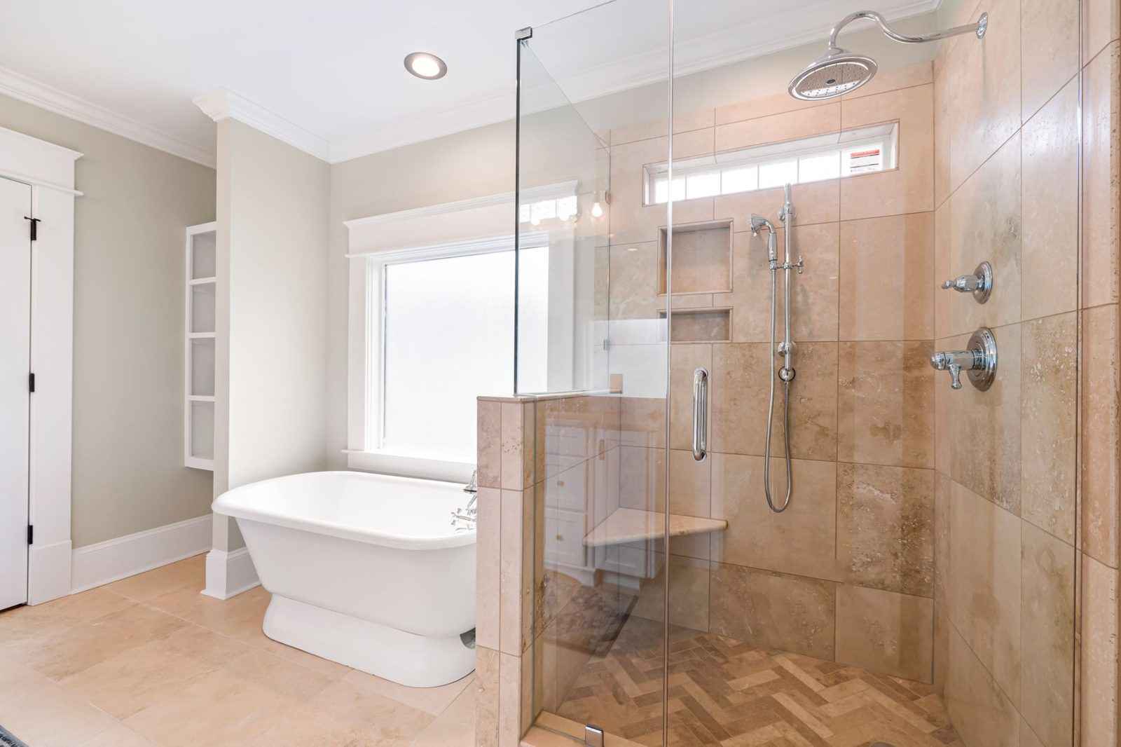 A bright bathroom with a freestanding bath and a frameless glass shower enclosure with a rain shower head