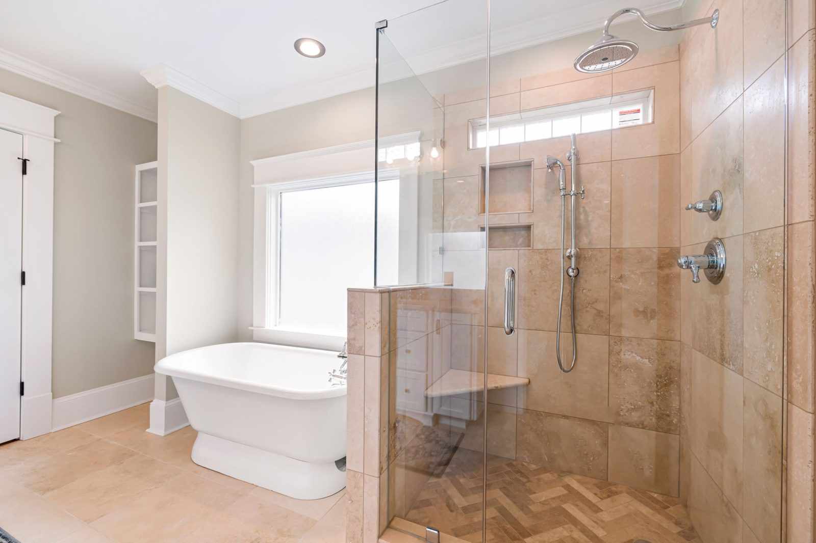 A bright bathroom with a freestanding bath and a frameless glass shower enclosure with a rain shower head